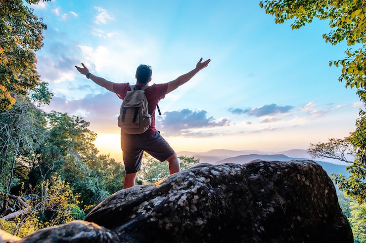 rear-view-back-young-asian-hiking-man-standing-riseup-hands-with-happy-peak-rocky-mountain-copy-space_1150-57186