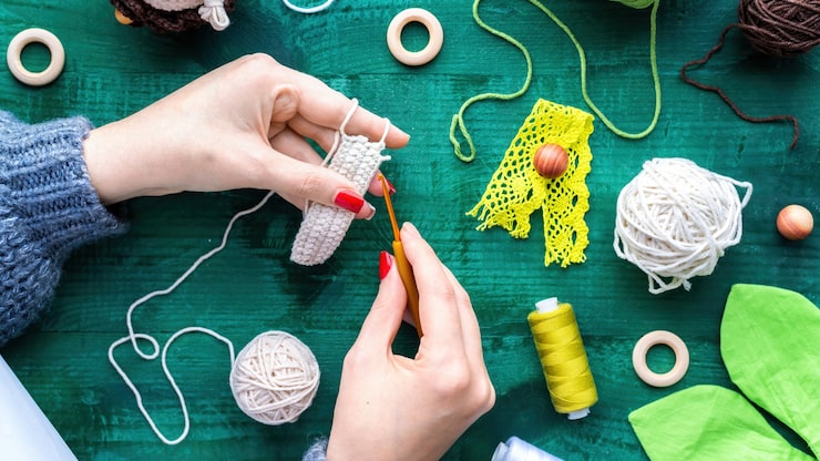woman-is-knitting-using-hooks-white-yarn-table-with-equipment_1268-17325